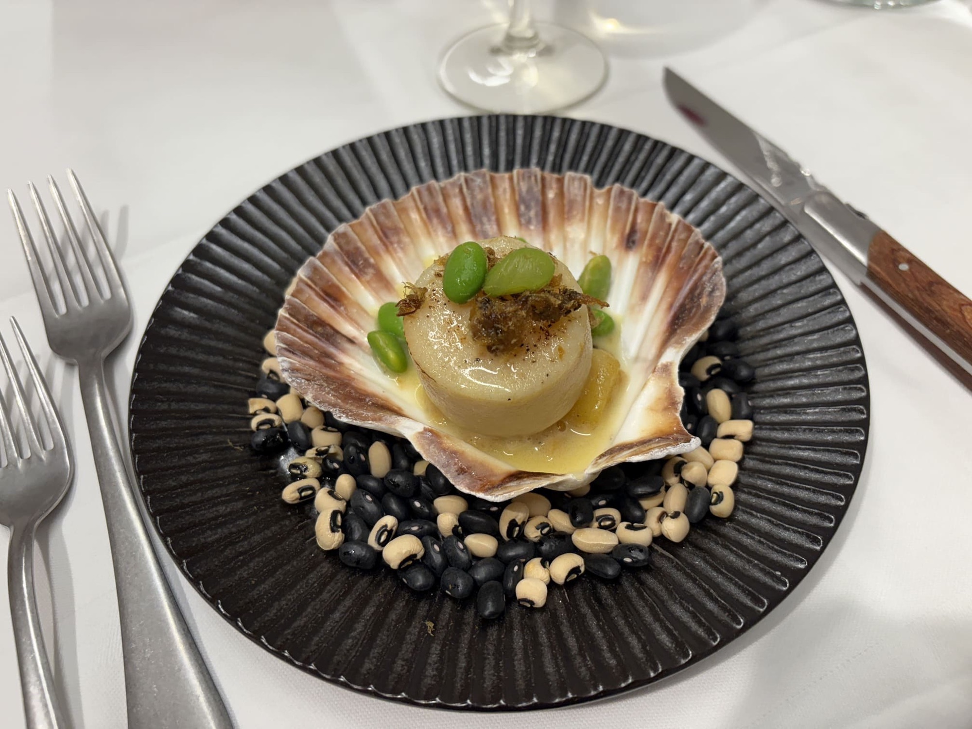Coquille op zwart aardewerk aan een gedekte tafel